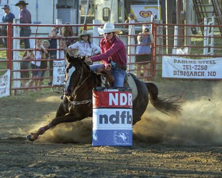 A barrel racer leans around the corner during a previous Wing Rodeo.